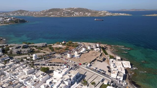 Aerial orbit view of famous windmills in Mykonos island, Greece from right to left on a sunny day with tourists taking photos.