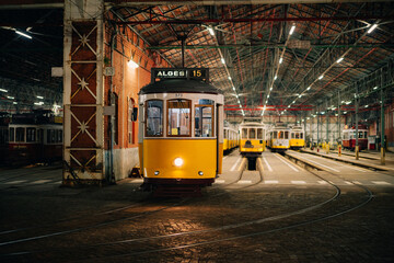 Iconic vintage yellow tram 15 resting in a Lisbon garage at night, symbolizing the city's charm and...