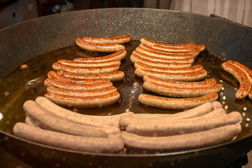 Sausages are fried in a pan, close-up. Delicious Sausage for sale on the street. Fast food. 