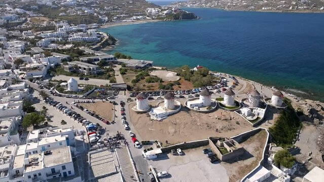 Aerial orbit shot of Windmills Mykonos, Greece  from right to left descending with tourists taking photos.