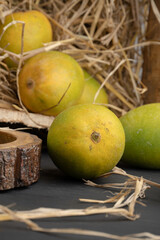 Mango heap in wood basket carrying by a orchard farmer with green leaf background.