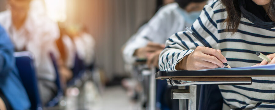 Exam at school with student's taking educational admission test in class, thinking hard, writing answer in university classroom, education and world literacy day concept