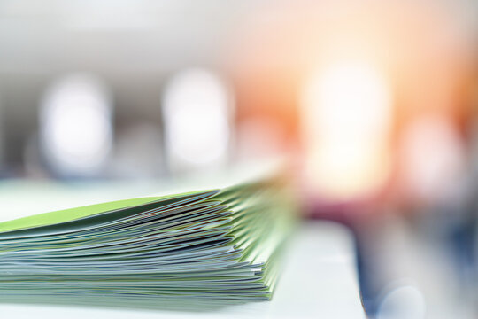 Exam answer sheet pile, blurry application document paperwork stack on office work table in examination room or classroom with blur education background school class university students taking test