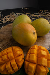 Mango tropical fruit with slice and half cut on green leaf background