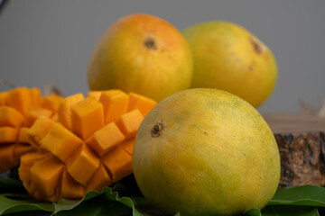 Mango tropical fruit with slice and half cut on green leaf background