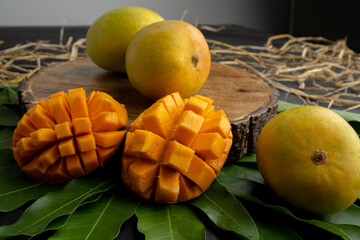 Mango tropical fruit with slice and half cut on green leaf background