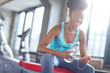 Smartphone, headphones and portrait of black woman in gym with water, fitness app or online...
