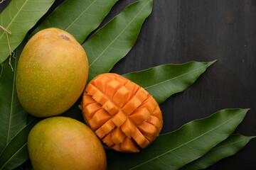 Mango tropical fruit with slice and half cut on green leaf background