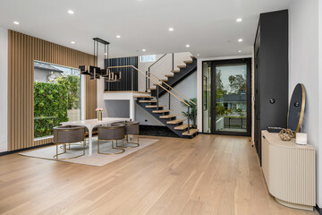 an open concept house with white walls, wood floors, and a staircase leading up