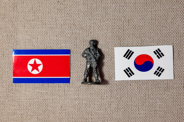 A soldier figurine on the background of the flags of North Korea and South Korea