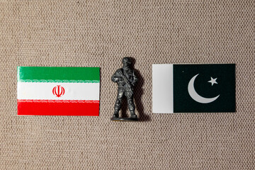 A soldier figurine on the background of the flags of Iran and Pakistan