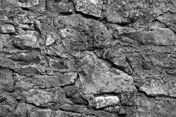 in the photo there is an old gray stone wall close up