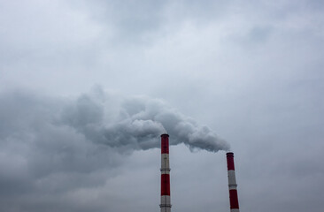 Smoke and steam from the pipes of a thermal power plant against a cloudy sky.