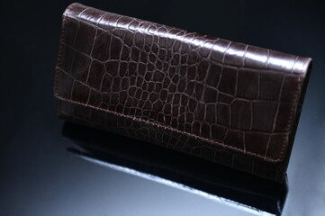 A dark brown color ladies' purse made with premium quality leather of crocodile skin texture,...