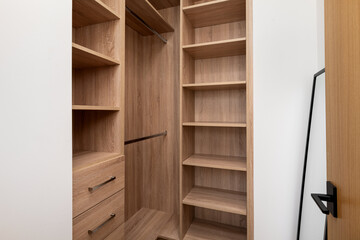 an empty wooden closet with a walk in closet space and a book shelf