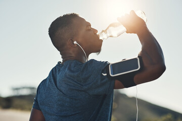 Black man, drink water and earphones in outdoors for running, thirst and hydrate on sports break. Person, profile and mineral liquid in bottle for nutrition, music and phone app for streaming song - obrazy, fototapety, plakaty