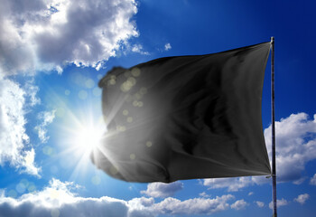 Conceptual image of waving blank black flag over sunny blue sky