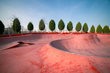 Skateboard in city. Skate and Bike Park. Extreme sports ground. Empty public pink skate park waiting for skaters. 