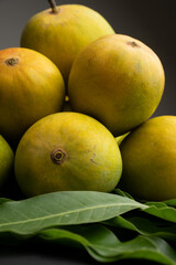 Mango heap in wood basket carrying by a orchard farmer with green leaf background.
