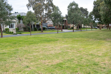 The vacant grass lawn in front of Australian suburban houses. A large public open green space in a local park for the residential neighborhood. Copy space for your design.