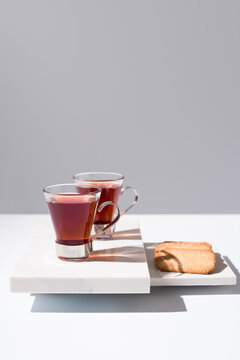 Dos tazas de té rojo con galletas sobre mármol y fondo gris