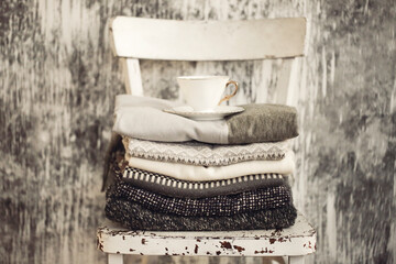 Pile of knitted warm grey and white blankets, scarves and woolen sweaters for winter or fall cold...