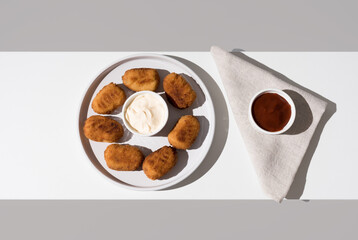 Plato de croquetas fritas con salsa de tomate y mayonesa aperitivo sobre fondo gris y blanco. Vista superior