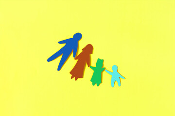 Cardboard figures of a family consisting of adults and children on a bright background. The concept of family relations.