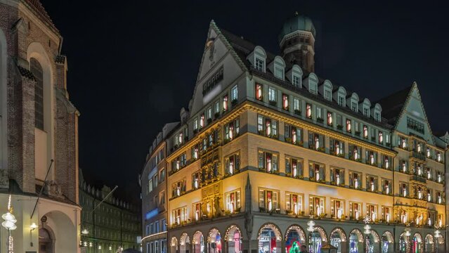 Kaufingerstrasse, shopping street and pedestrian zone in Munich downtown near the Marienplatz night timelapse. Panorama of historic buildings with people walking around. Bavaria, Germany