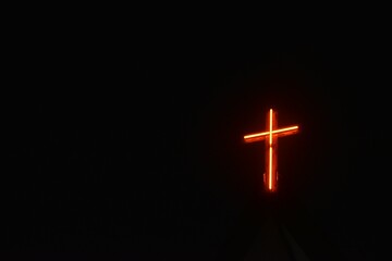red lamp bulb light in cross on rooftop of Christian church in night sky background