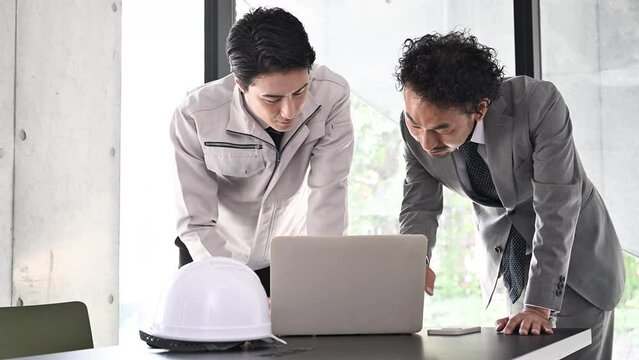 施工図を確認する現場監督と施工管理技士　不動産、ビルの設計や施工管理などのイメージ　笑顔で打ち合わせのの動画