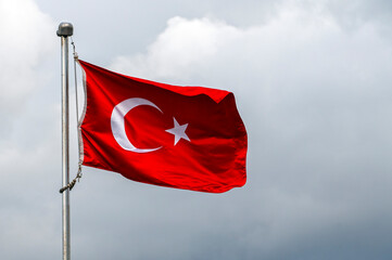 The national flag of Turkey, officially the Turkish flag against cloudy sky in Istanbul