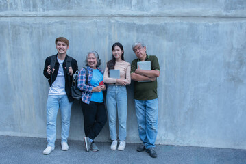Group of Asian students, old people and children Standing against the wall taking pictures together on campus Review the lesson together adult education concept