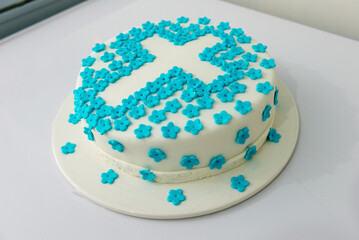 A blue and white cake with a cross made of flowers on top