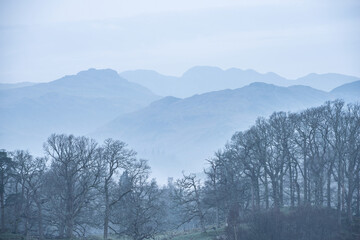 Stunning peaceful landscape image of misty Spring morning over Windermere in Lake District and distant misty peaks - 783776449