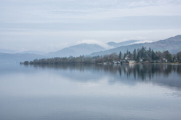 Stunning peaceful landscape image of misty Spring morning over Windermere in Lake District and distant misty peaks - 783776480