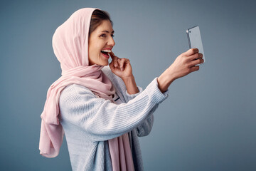 Islamic woman, selfie and influencer with smile, happiness and social media on grey studio...