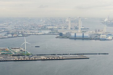 Aerial View of a Bustling Port City With Modern Wind Turbine on Overcast Day