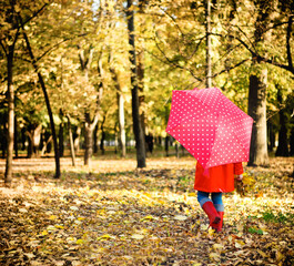 Little girl with polka dots umbrella walking through alley