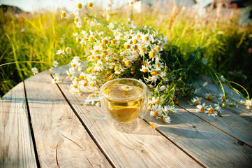 A cup of aromatic herbal tea with chamomile on a wooden table
