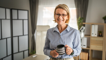 Mature woman with cup of coffee have a break at work
