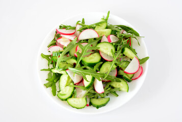 a plate of salad with radish, cucumber and arugula isolated on white  