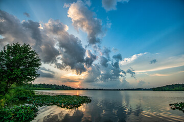 Cloudscape and sunbeams over lake at sunset