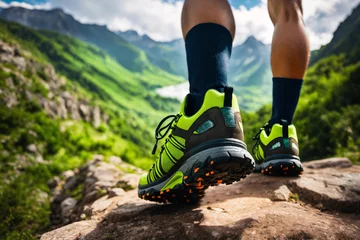 Foto op Canvas The legs in socks of a man traveler going in hiking green sneakers shoes for cross-country travel. Back view. Green highland on background. © nskyr2