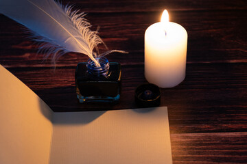 Ink, feather and candle on a table