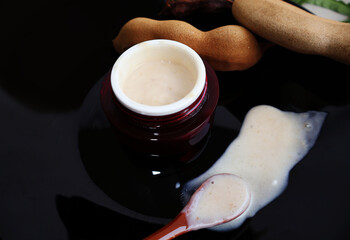 Skin cream containing ingredients from ripe tamarind pulp in a red jar. Scoop out the cream and...