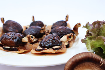 Shiitake mushrooms, minced pork, chicken ham, steamed, poured with sauce, vegetables on the side of the plate, white background.

