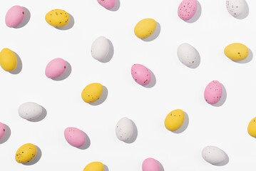 Pattern of chocolate Easter eggs in white, pink and yellow colors on a white background. Creative...