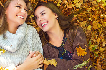 Fashionable beautiful young girlfriends together in the autumn park background. Having fun and...