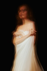 Dramatic portrait of lovely young girl on black background. Blurry effect, long exposure